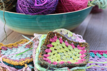 Closeup detail of crochet work grannysquare with a colourful skein of organic natural handspun and...
