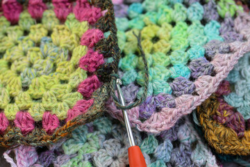 Closeup detail of crochet work grannysquare with a colourful skein of organic natural handspun and...