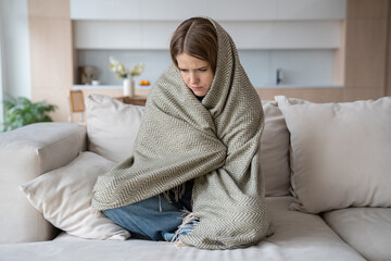 Desperated depressed woman crying sitting on couch with closed eyes wrapped in plaid. Girl suffering fom emotional pain having life troubles problems. Mental disorder, anhedonia, stress, sleepiness.
