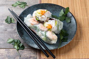 Vietnamese spring rolls with vegetables, rice noodles and prawns on wooden table