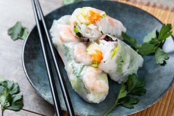 Vietnamese spring rolls with vegetables, rice noodles and prawns on wooden table. Close up