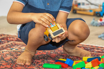 wooden children toys, bulldozer and colorful cubes on the carpet, in the children room