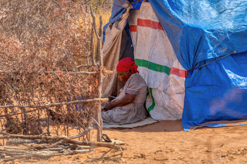 destitute camp people migration , informal settlement in the bush, woman in front of the shack,...