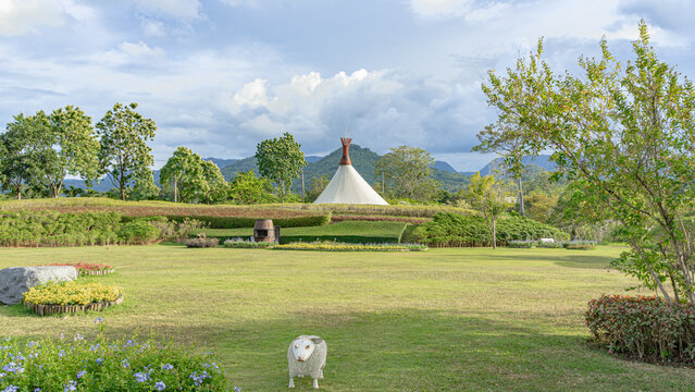 A picture of a large courtyard. There is a sheep doll waiting to welcome you in front. Behind it is a large Indian tent. Located amidst a beautiful garden.