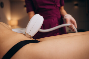 Professional beautician removes hair on beautiful female tummy using a laser. hair removal on the belly, laser procedure at clinic