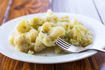 Cooked cauliflower, steamed, in a plate with spices .