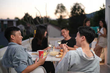 Group of friends hanging out together talking and having fun on a rooftop party