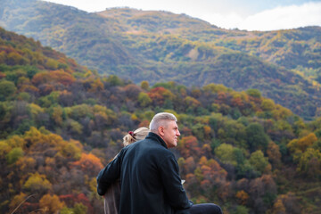 Naklejka na ściany i meble Loving couple in the mountains enjoying the scenery in their arms