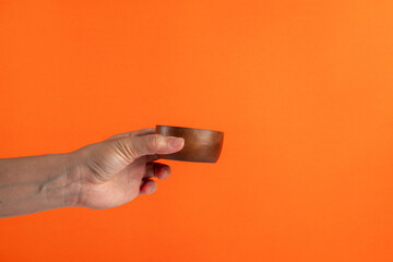Cup wooden in hand on orange background
