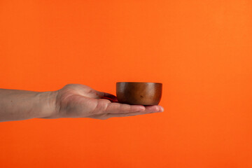 Cup wooden in hand on orange background