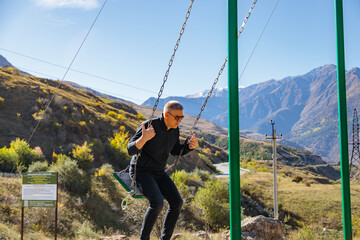 Man relaxing on a swing while enjoying the surrounding mountains and vast landscape