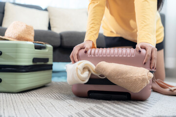 Fototapeta premium A young woman packing clothes into a suitcase for her travels