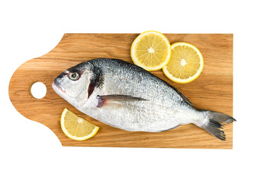 Raw fish Dorado with lemon on a cutting board isolated on a white background. Top view.