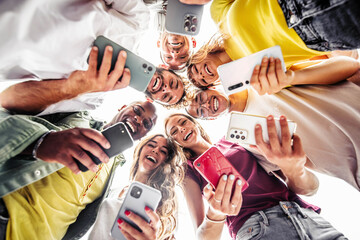 Fototapeta premium Teens in circle holding smart mobile phones - Multicultural young people using cellphones outside - Teenagers addicted to new technology concept