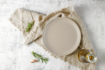 Empty beige vintage plate with olive oil bottle and rosemary herb over linen towel.
