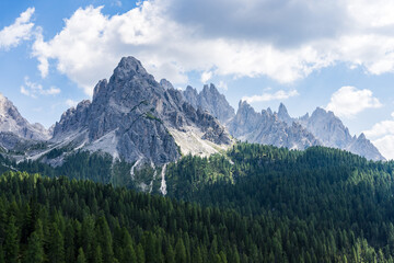 Fototapeta na wymiar Majestic Dolomite peak in the Italian Alps on a warm summer day with pine trees in the foreground