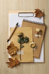 Dried plants, notepads and pen on wooden background, top view