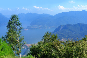 Fototapeta na wymiar idyllic Mountain Landscape Photography at Lake Como, green hills above Lake Como in Italy, mountains against backdrop of blue sky, concept of tourist season, tourism destination