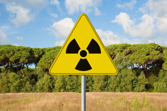 Danger of radioactive contamination from RADON GAS - concept with warning symbol of radioactivity on road sign against a building lot and vacant land available for building construction