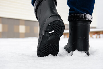Man in black insulated boots for hunting, fishing and traveling in winter.
