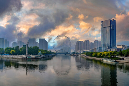 Serene Dawn or Dusk Cityscape with Calm River, Ferris Wheel Silhouette, and Modern High-Rises
