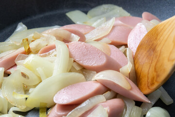 魚肉ソーセージと玉ねぎをフライパンで炒める調理シーン。
