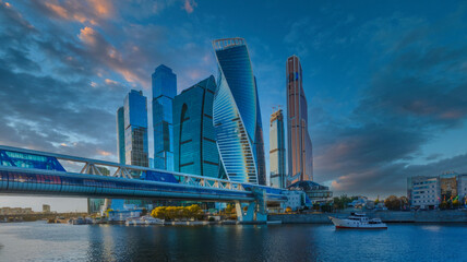 Futuristic Cityscape at Dawn or Dusk with Reflective Water, Modern Skyscrapers, and Pedestrian Bridge