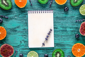 mockup cut citrus, lavender, blueberry, notebook on blue desk background top view