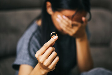 Unhappy woman holding wedding ring, suffering from relations breakup or getting divorced.
