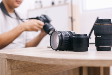 Various of lenses on wooden table against blurry background of photographer setting professional...