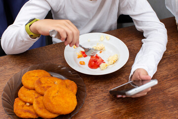 An unrecognizable man eats food from a plate.