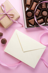 Love letter for Valentine day. Envelope from craft paper with  chocolate candies, gifts and ribbons on light pink background. Lover's holiday confession or proposal concept. Flat lay, top view. 