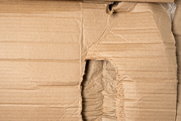 Brown corrugated cardboard with a hole and wrinkles. Damaged package