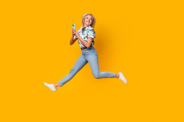Full length photo of optimistic woman wear blouse denim pants jumping with smartphone in hands...