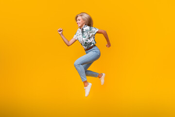 Fototapeta na wymiar Full size photo of fast active girl dressed print shirt running look at proposition empty space isolated on yellow color background