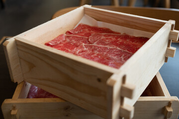 Premium quality sliced beef meat with a perfect fatty texture served on wood box for sukiyaki or...