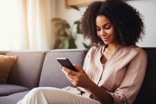 African american young woman using cellphone sitting in the living room