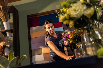 Young woman working in her flower shop making bouquet.