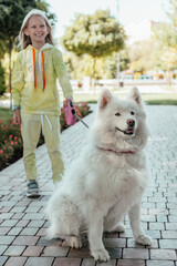 A girl walking with a dog in the park. Dog on a leash.