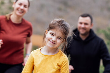 Happy family jogging in the summertime. Smiling young couple with their cute daughter doing sport