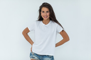 Beautiful brunette girl in a white T-shirt and denim shorts posing 