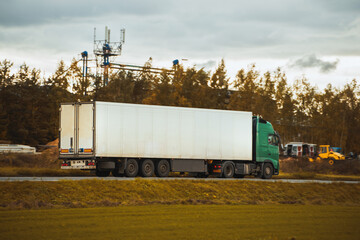 Fototapeta na wymiar Side view of truck with semitrailer shipping goods on the highway. Sustainable future global supply chain. Export and import in the EU economic zone. Logistics and shipping concept.