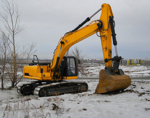 Yellow excavator in winter. Winter construction. Yellow excavator at a construction site. Heavy industry machine. Ust-Kamenogorsk (kazakhstan)