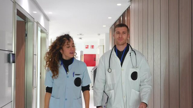 Team work of a female nurse and doctor talking in the corridor of an hospital