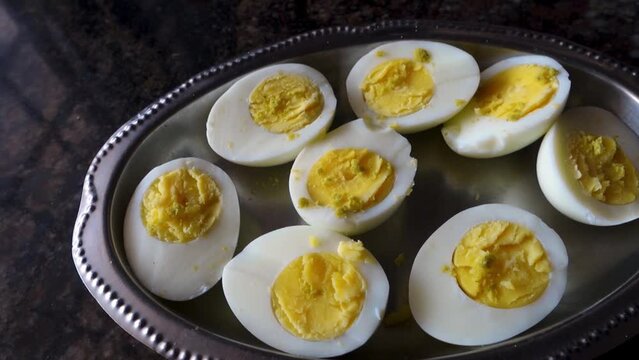 A close up shot of boiled eggs cut in half with seasoning on top.India