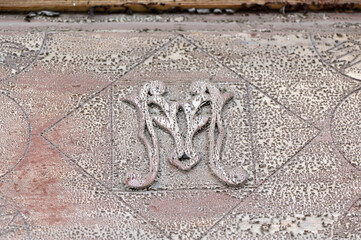 Der Buchstabe M auf einer alten spanischen Tür. Eine alte, sehr verwitterte Holzschnitzerei.