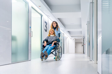 Healthcare worker pushing a wheelchair with injured woman - obrazy, fototapety, plakaty