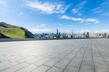 Empty square floor and green mountain with city skyline landscape under blue sky. High Angle view.