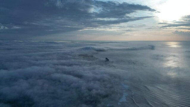 Aerial hyperlapse footage glides over ocean, captures tranquil sunrise at beach. Coastline meets rolling clouds, seabirds soar. Ideal for travel vlogs, nature documentaries, serene scenes.