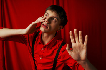 suspenseful man in shirt with suspenders posing with raised hands on red background, startled